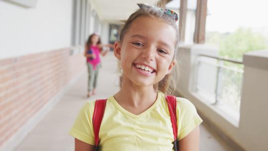 快乐的女孩站在学校走廊上