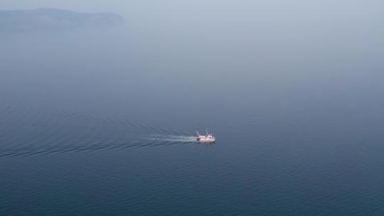 早上在平静的蓝色大海上行驶的渔船，空中