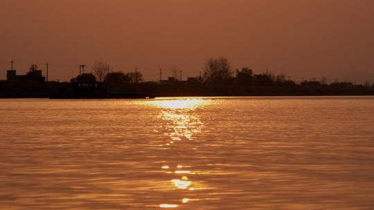 傍晚夕阳落日逆光金色水面轮船剪影