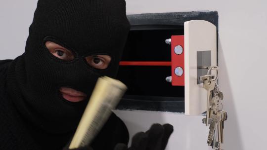 一个戴着黑色面具的强盗打开保险箱偷钱