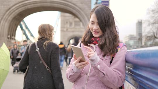 女孩在伦敦塔桥上使用手机