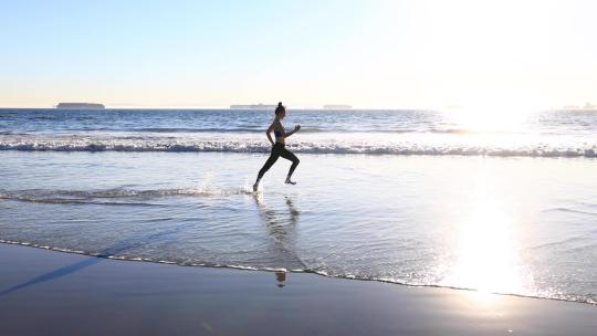 女人在阳光明媚的海边慢跑