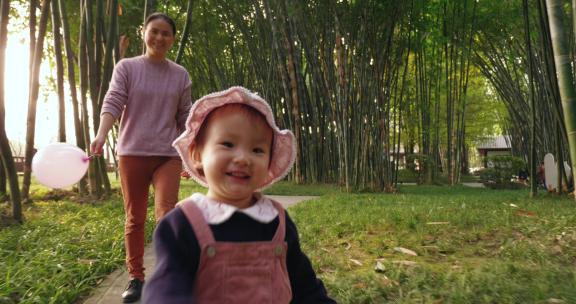 刚学步的小女孩和妈妈在公园里散步