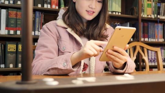 女留学生在图书馆使用电子设备学习