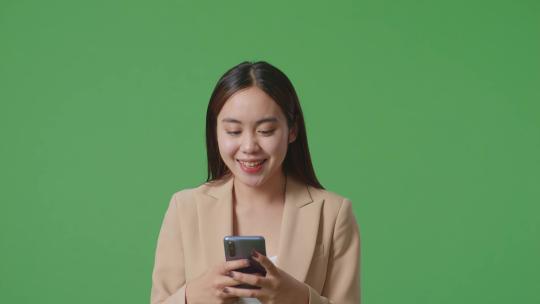 亚洲商务女性使用手机和走在绿屏色度键的特写