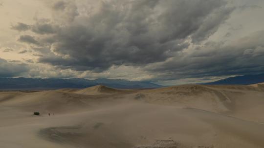 从多云的天空缓缓向下平移到潮湿的沙丘，沙子上有脚印