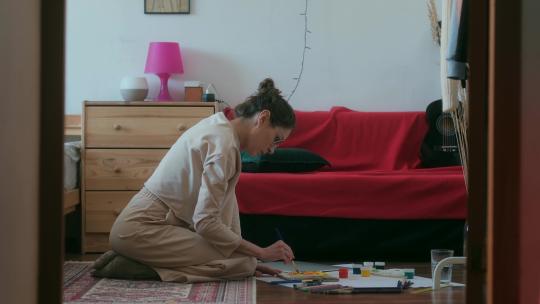 年轻的黑发女人在家画画视频素材模板下载