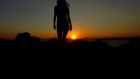 日落时走在岛上的女孩