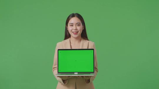 一名亚洲女商人在工作室的绿屏背景上展示笔记本电脑绿屏视频素材模板下载