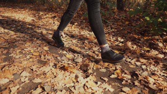 白天，十几岁的女孩独自走在秋天的森林里，脚的特写