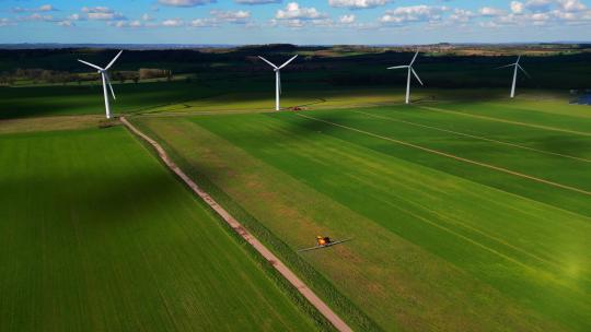 FPV航拍绿色农场中的风力发电机和播种机