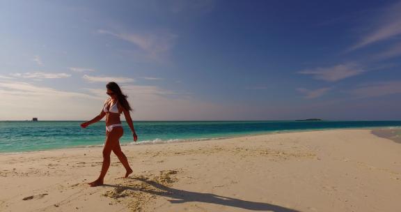 美丽的美女模特在天堂白沙和蓝色的海滩上晒太阳放松