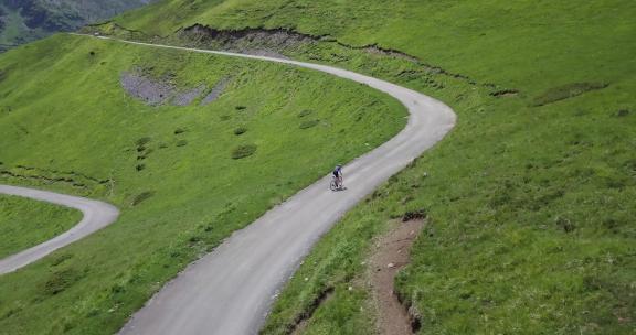 一男子骑自行车行驶在山间的公路上
