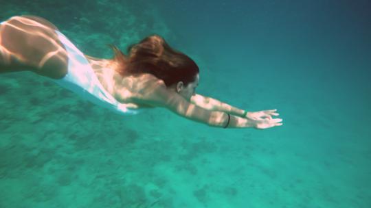 穿着蓝色泳衣的女人在水下慢动作游泳
