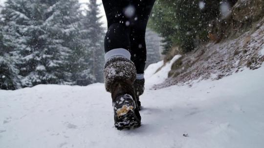 慢动作的女人的靴子行走扔了一片雪林，非常明显的降雪展示了