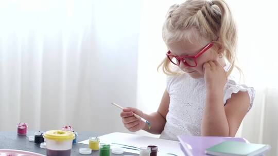 一个戴着眼镜的年轻女孩忙于作画
