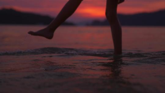 女孩光脚站在日落海滩边