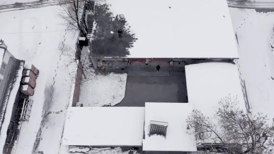 俯拍冬天房顶扫雪