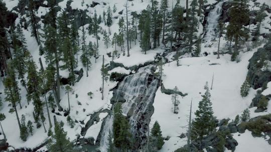 轨道无人机从右到左拍摄了冬季雪山中一个较小的瀑布