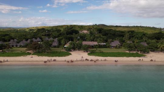 静态无人机观察人们沿着斐济纳塔多拉海滩骑马