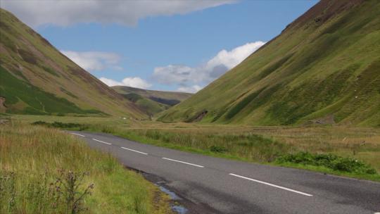 英国莫法特——2017年8月3日：一辆汽车沿着风景优美的苏格兰边境山脉之间风景优美的A708公路行驶