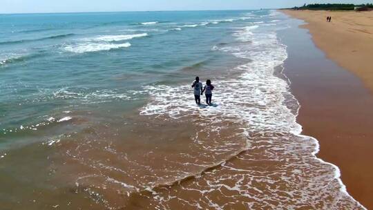 无人机拍摄到两个人站在海滩上