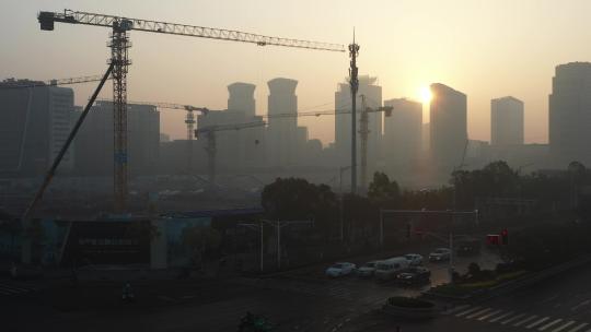 日出雾霾中的工地和远处的高楼