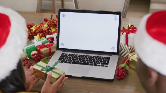 戴着圣诞帽的快乐多样化夫妇在有复制空间的笔记本电脑上进行圣诞视频通话的视频