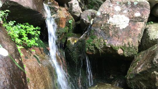 山林里顺岩石而下的瀑布泉水