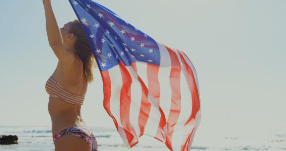 女孩在海滩上举着国旗
