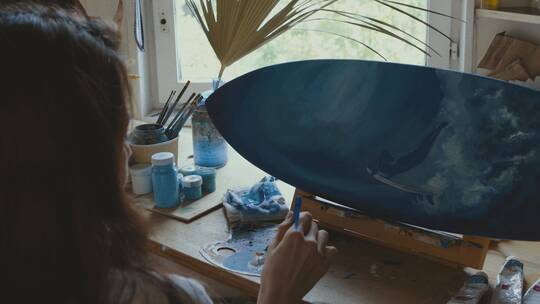 一个女人正在用蓝色油漆板画画