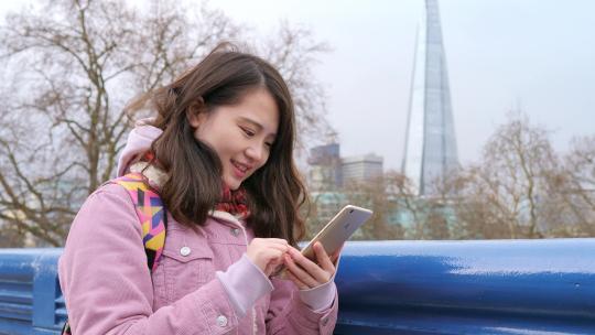 女孩在伦敦塔桥上使用手机
