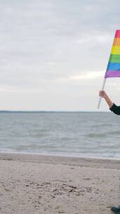 在海滩上举着彩虹旗的女人竖屏