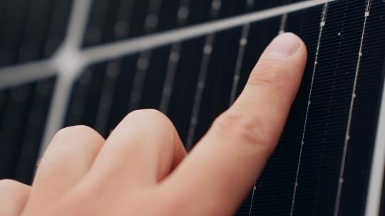 人手指触摸太阳能电池板的特写宏观视图