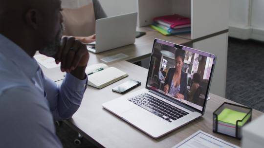 非裔美国高级男子在办公室的笔记本电脑上与女同事进行视频通话视频素材模板下载