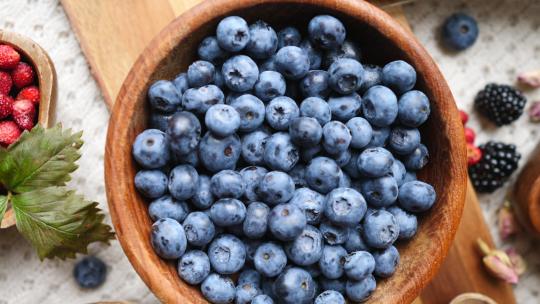 健康食品理念蓝色餐桌上的混合浆果蓝莓