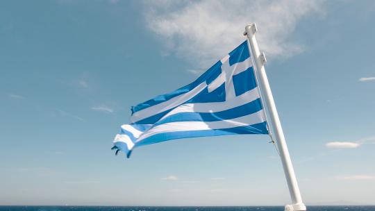 公海上渡轮背面迎风飘扬的希腊国旗特写镜头，机器人中有一条细长的水带