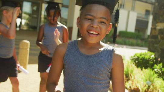 快乐的非裔美国男孩在学校前戴着毕业帽的视频
