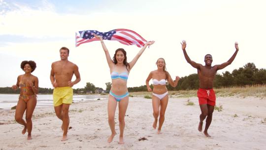 朋友与美国国旗运行在夏季海滩34