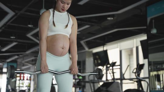 现代女性怀孕的妇女在健身房锻炼身体撸铁
