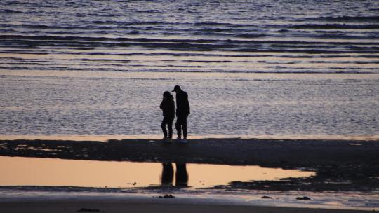 夕阳沙滩上漫步的情侣