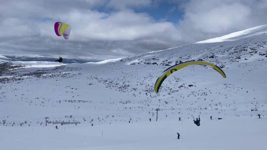 4K滑翔伞运动飞行在蓝天白云雪山滑雪场