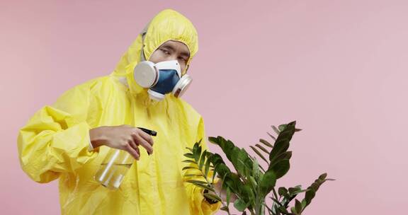 一个穿着防护服和防毒面具的男人正在给植物浇水
