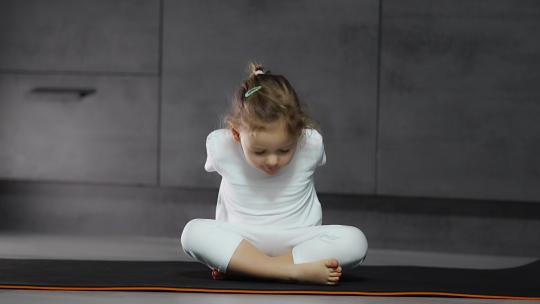 小女孩瑜伽垫上练习瑜伽视频素材模板下载