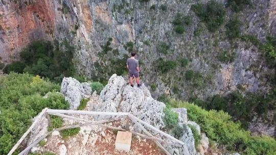 航拍男子站在悬崖边眺望峡谷视频素材模板下载