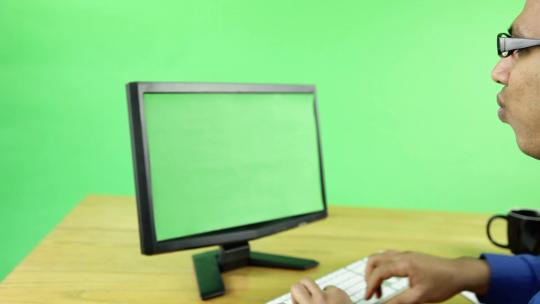 男子在绿色电脑屏幕和背景前说话