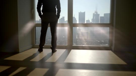 站在大窗前的城市现代办公室里的男人剪影