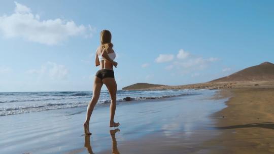 运动女性沿着沙滩跑步