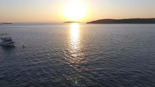 夕阳下的渔船航行与夕阳在海上的反射