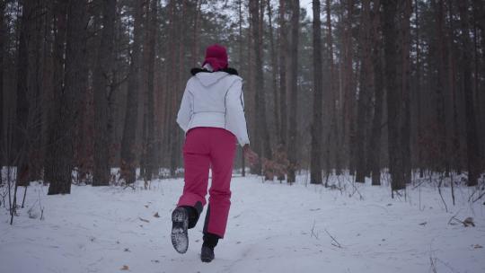 跑过冬季森林的非裔美国女孩。穿着温暖夹克的美丽女孩转身环顾四周，她很害怕。女人被看不见的追逐者追逐